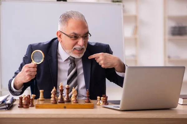 Viejo empleado jugando ajedrez en el lugar de trabajo — Foto de Stock