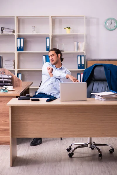 Joven empleado masculino estirándose en el lugar de trabajo —  Fotos de Stock