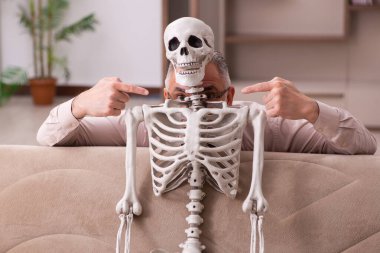 Kanepede oturan yaşlı adam ve kadın iskeleti.