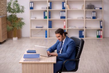 Genç erkek çalışan ofiste oturuyor.