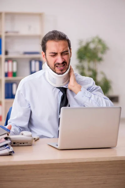 Cuello joven lesionado empleado masculino que trabaja en la oficina — Foto de Stock