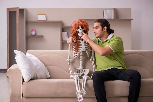 Jongeman zittend op de bank met vrouwelijk skelet — Stockfoto