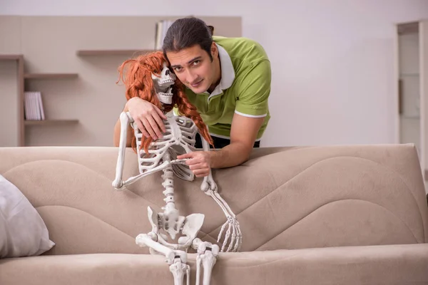 Jongeman zittend op de bank met vrouwelijk skelet — Stockfoto