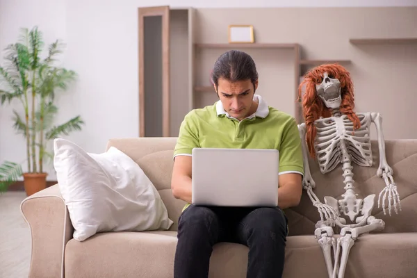 Jongeman zittend op de bank met vrouwelijk skelet — Stockfoto