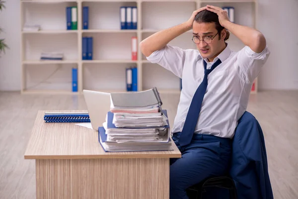Jonge mannelijke werknemer en veel werk op kantoor — Stockfoto