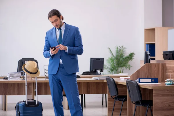 Junge männliche Angestellte bereitet sich im Büro auf Reise vor — Stockfoto