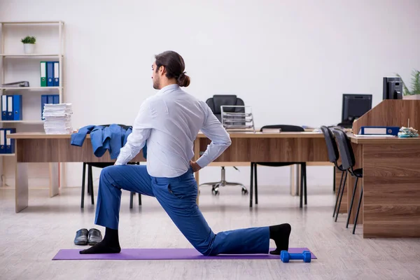 Joven empleado masculino haciendo ejercicios deportivos durante el descanso — Foto de Stock