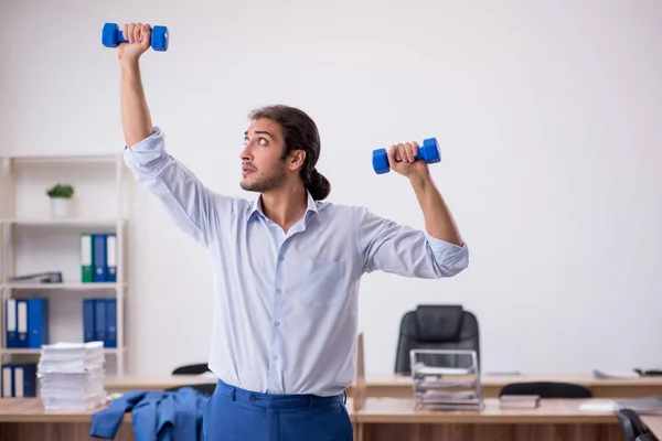 Joven empleado masculino haciendo ejercicios deportivos durante el descanso —  Fotos de Stock