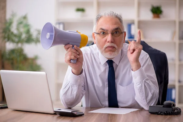 Gammal manlig anställd som håller megafon på arbetsplatsen — Stockfoto