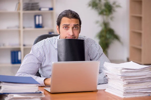 Jonge mannelijke werknemer ongelukkig met overmatig werk in het kantoor — Stockfoto