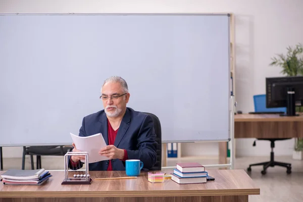 Stary nauczyciel fizyk siedzi w klasie — Zdjęcie stockowe
