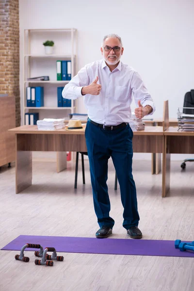 Oude zakenman werknemer doet sport oefeningen in het kantoor — Stockfoto