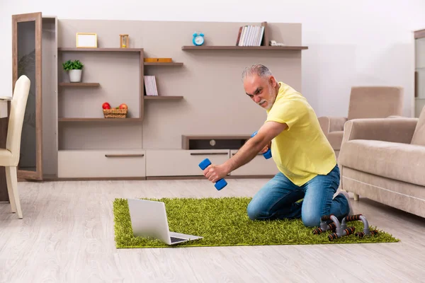 Homem idoso fazendo exercícios esportivos em casa — Fotografia de Stock