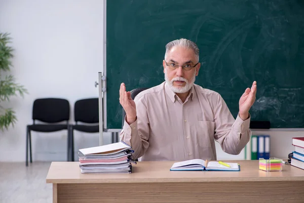 Alte männliche Lehrer sitzen im Klassenzimmer — Stockfoto