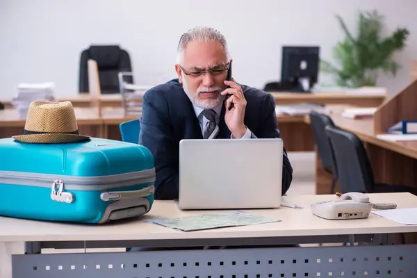 Old male employee preparing for travel in the office — Stock Photo, Image