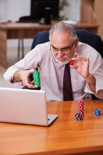 Oude mannelijke werknemer in het gokconcept op de werkplek — Stockfoto