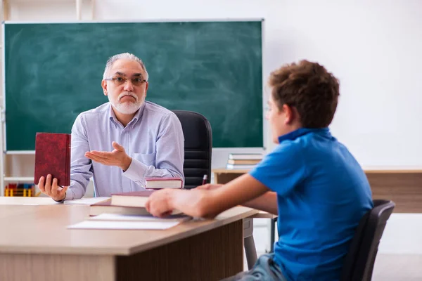 Oude mannelijke leraar en schooljongen in de klas — Stockfoto