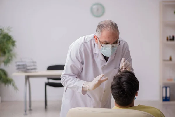 Genç erkek hasta yaşlı doktor otorhinolaryngologis 'i ziyaret ediyor. — Stok fotoğraf