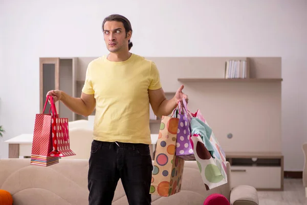 Joven con muchas bolsas en concepto de Navidad en casa — Foto de Stock