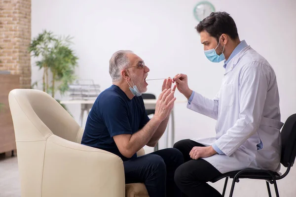 Yaşlı erkek hasta genç doktor otorhinolaryngologis 'i ziyaret ediyor. — Stok fotoğraf