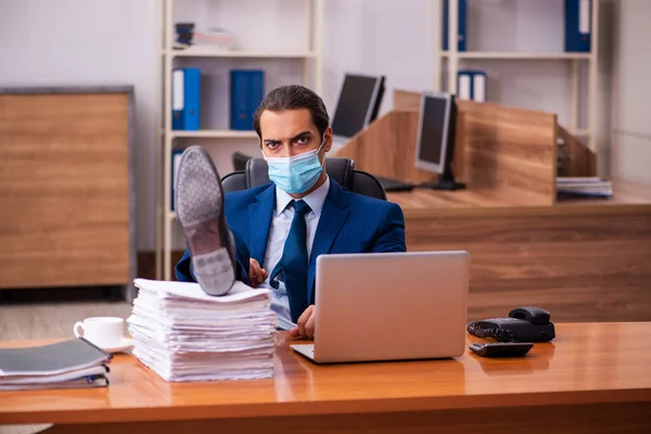 Молодой работник, работающий в офисе в маске — стоковое фото