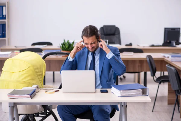 Young male employee looking after new born at workplace