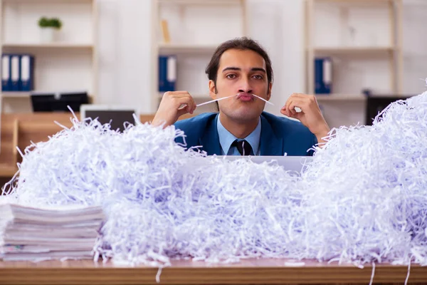 Jonge mannelijke werknemer en veel gesneden papieren in het kantoor — Stockfoto