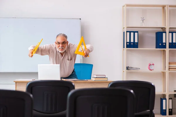 Oude mannelijke meetkundeleraar in het klaslokaal in pandemisch concept — Stockfoto