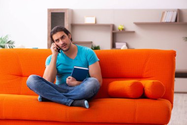 Genç erkek öğrenci turuncu koltukta oturuyor.