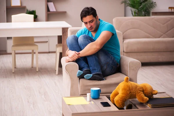 Fiatal férfi ül medve játék otthon — Stock Fotó