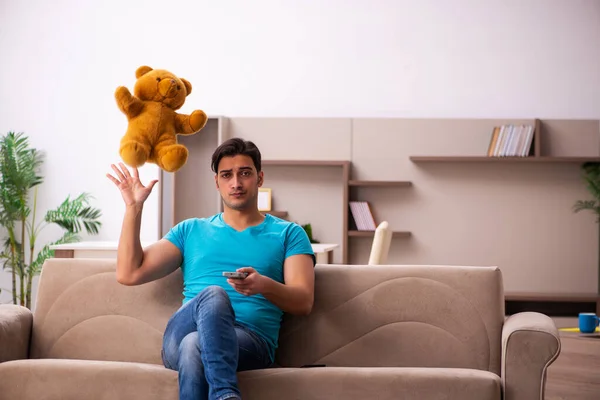 Young man sitting with bear toy at home