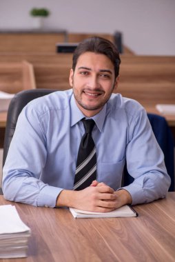 Genç bir erkek çalışan ve ofiste çok fazla iş var.