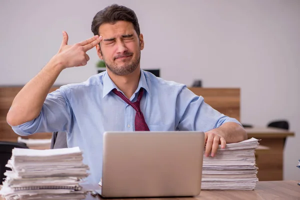 Jonge mannelijke werknemer ongelukkig met overmatig werk in het kantoor — Stockfoto