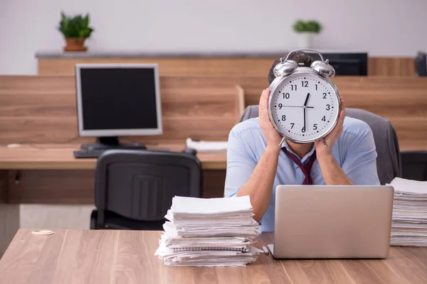 Jonge mannelijke werknemer ongelukkig met overmatig werk in het kantoor — Stockfoto