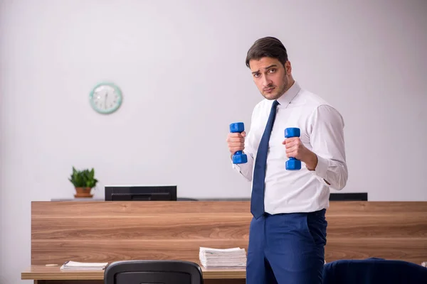 Jonge zakenman die sport-oefeningen doet op de werkplek — Stockfoto