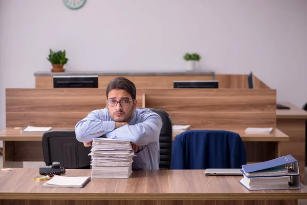 Ung manlig anställd och för mycket arbete på kontoret — Stockfoto