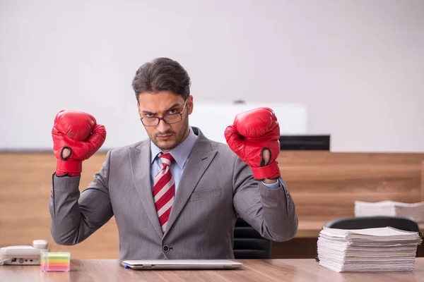 Junge männliche Angestellte trägt am Arbeitsplatz Boxhandschuhe — Stockfoto