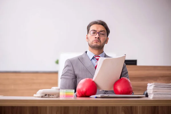 Junge männliche Angestellte trägt am Arbeitsplatz Boxhandschuhe — Stockfoto