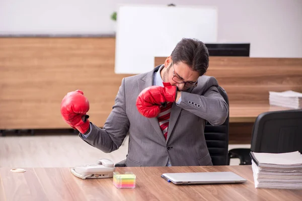 Ung man anställd bär boxningshandskar på arbetsplatsen — Stockfoto