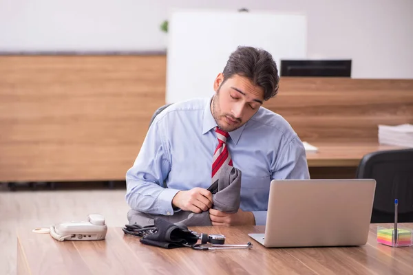 Joven empleado masculino que sufre de hipertensión en el lugar de trabajo —  Fotos de Stock