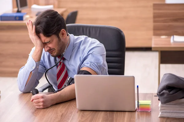 Ung manlig anställd som lider av högt blodtryck på arbetsplatsen — Stockfoto