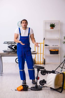 Genç erkek tamirci perambulator tamir ediyor.