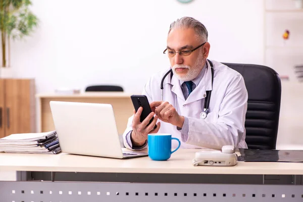 Verouderde mannelijke arts werkzaam in de kliniek — Stockfoto