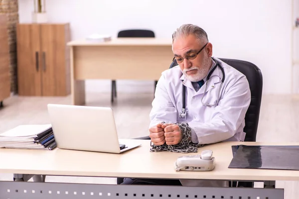 Geketende oudere mannelijke arts die in de kliniek werkt — Stockfoto