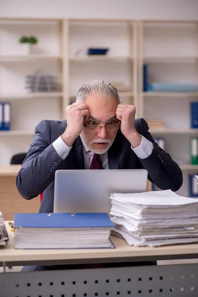 Überalterte männliche Mitarbeiter und zu viel Arbeit am Arbeitsplatz — Stockfoto