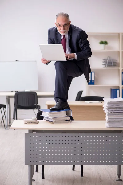 Dipendente di sesso maschile anziano e troppo lavoro sul posto di lavoro — Foto Stock