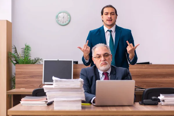 Viejo empleador masculino y joven asistente masculino en concepto de bullying — Foto de Stock