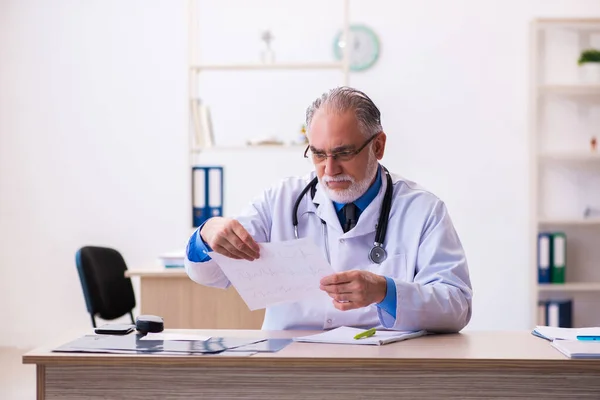 Öreg férfi orvos kardiológus keres elektrokardiogram — Stock Fotó