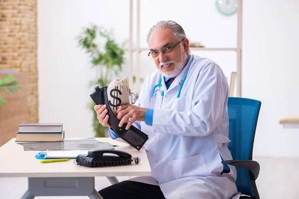 Yaşlı doktor hastanede para çantasını tutuyor. — Stok fotoğraf