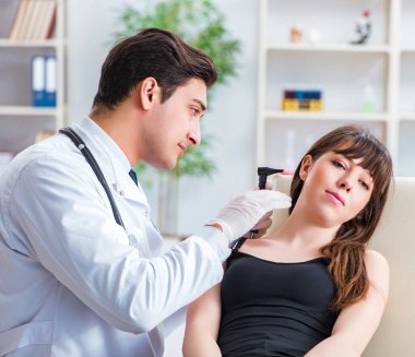 Doktor muayene sırasında hastaların kulaklarını kontrol ediyor.